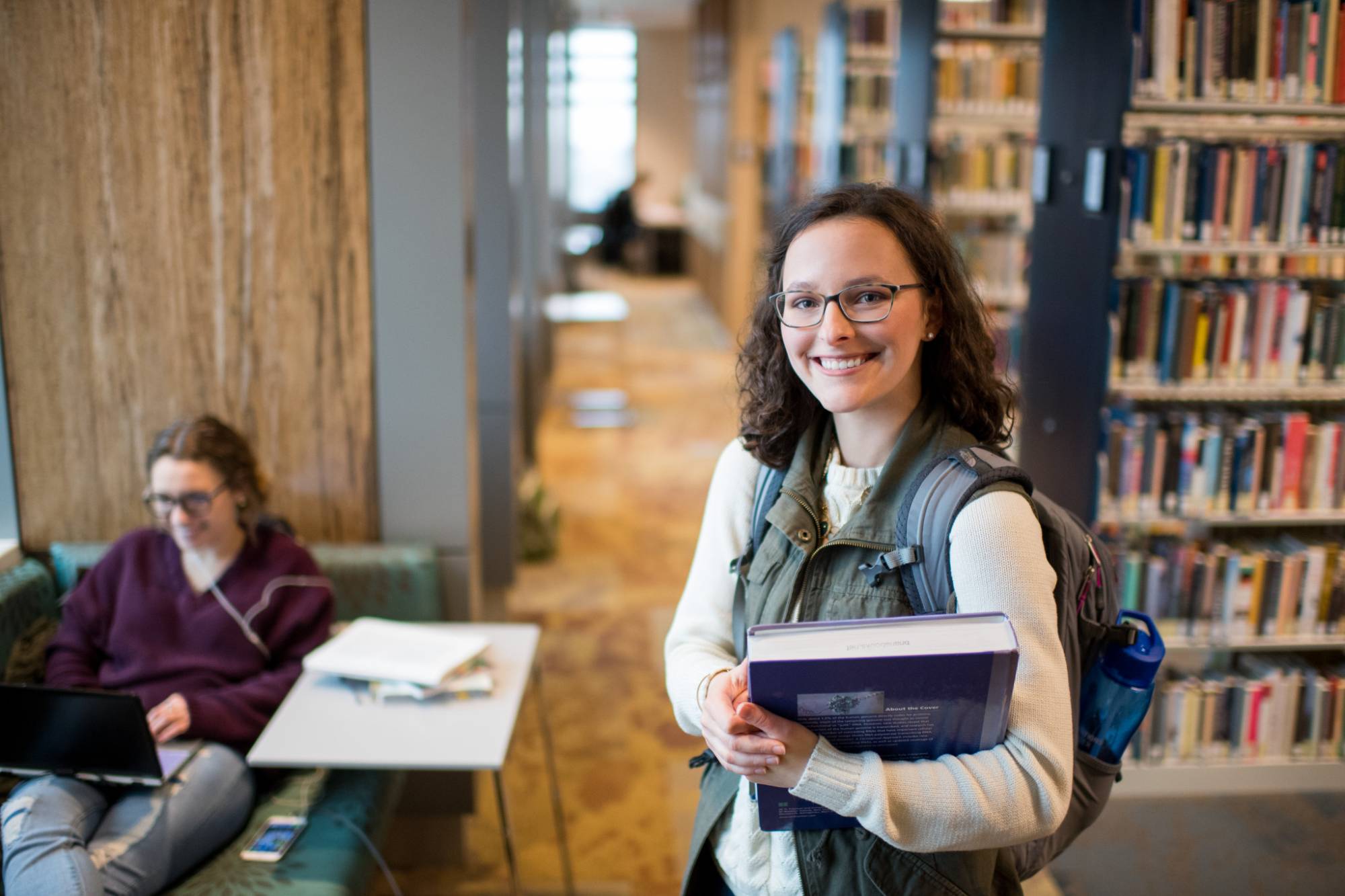 Student holding a book in GVSU library